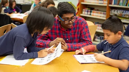 Student tutoring two elementary school students